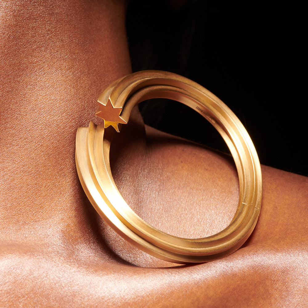 Goldstar twin star motif shooting star bangle in 18 karat yellow gold by Solange Azagury-Partridge on models neck