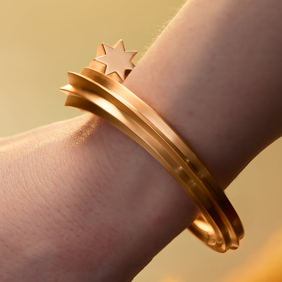 Goldstar twin star motif shooting star bangle in 18 karat yellow gold by Solange Azagury-Partridge on wrist