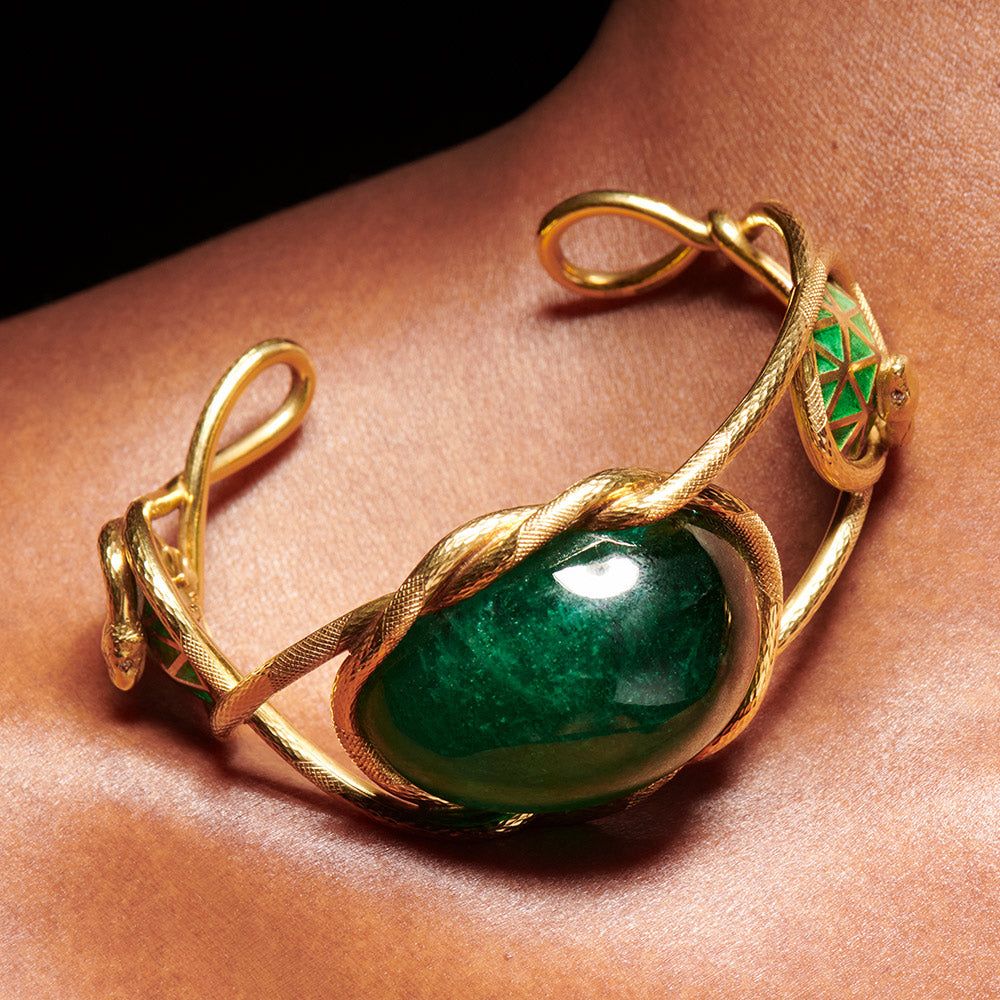 Treasure bangle of an emerald snake motif encircling emerald cabochon in 18 karat yellow gold by Solange Azagury-Partridge on models neck