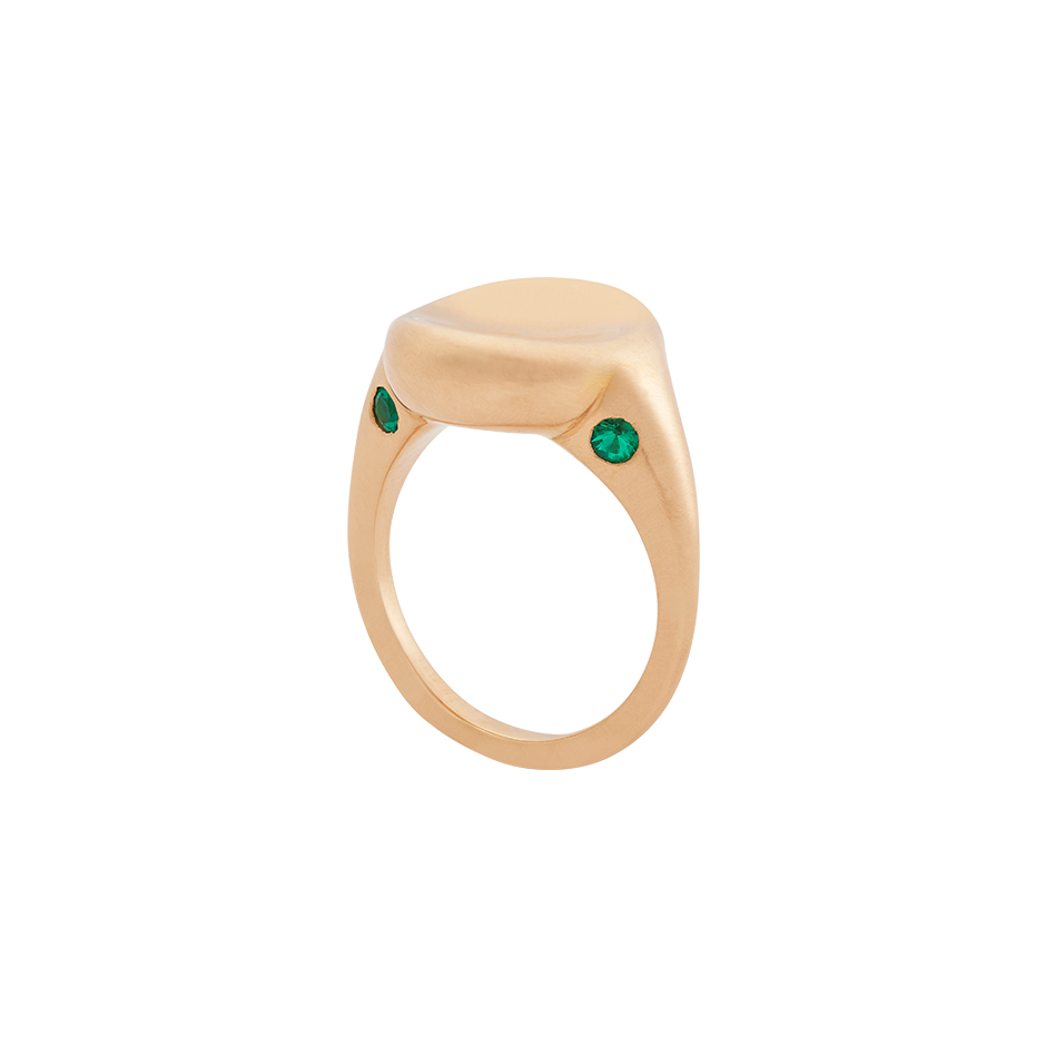 A ring with a round concave top set with two emeralds on the front and back in 18 karat yellow gold ring y Solange Azagury-Partridge