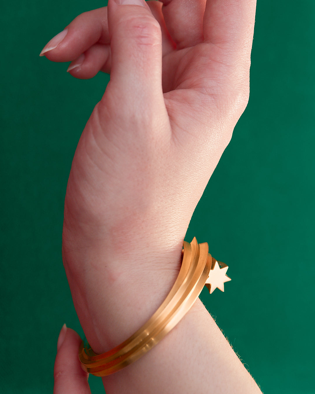 Goldstar twin star motif shooting star bangle in 18 karat yellow gold by Solange Azagury-Partridge on wrist